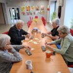 Grupa seniorów siedzi przy stole i gra w gry planszowe