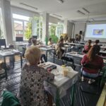 warsztaty malarskie, grupa osób pracuje przy stolikach