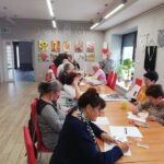 uczestnicy zajęć artystycznych malują przy stole