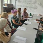 grupa uczestników warsztatów siedzi przy stole i rozmawia