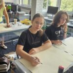 3 osoby malują na stołach