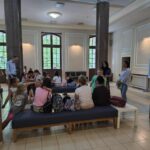 ludzie siedzący na ławkach, w holu Teatru Lalek