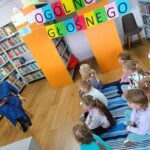 dzieci siedzą na kocyku, słuchają opowiadania