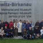 grupa osób pozuje na tle ściany muzeum