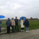 6 osób, w tle obóz Auschwitz-Birkenau