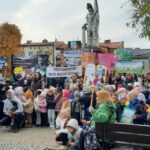grupa dzieci i młodzieży stoi pod pomnikiem św. Floriana