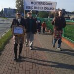 młodzież stoi na chodniku, trzyma w ręce transparent z napisem : Międzynarodowy miesiąc bibliotek szkolnych