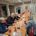grupa osób siedzi przy stole z grami planszowymi