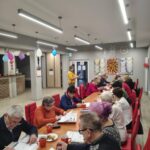 grupa osób siedzi na krzesłach i wykonuje zadania na pamięć i koncentrację