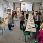 grupa osób wykonuje gimnastykę przy krzesłach