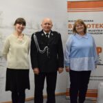 dwie kobiety i mężczyzna stoja przy ścianie