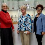 trzy kobiety stoją przed gablotą biblioteczna