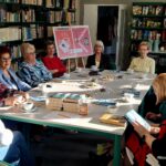 grupa kobiet siedzi przy stole w czytelni biblioteki