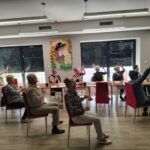 grupa seniorów wykonuje gimnastykę na krzesełkach