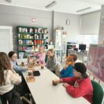 Młodzież DKK siedzi przy stole i dyskutuje o książce