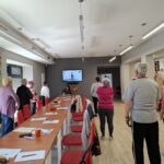 grupa seniorów wykonuje gimnastykę na stojąco