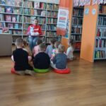 bibliotekarka trzyma jednorożca, który opowiada dzieciom bajki