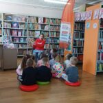 bibliotekarka czyta bajkę, w tle regały z książkami