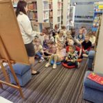 Bibliotekarz opowiada dzieciom jak wygląda droga książki od pomysłu autora do książki w bibliotece