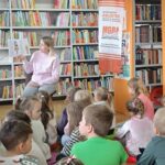 dzieci siedzą na poduszkach, słuchają historii o dzielnym Wojtku