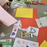 dzieci robią laurki, na stole rozłożone potrzebne materiały