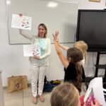 bibliotekarka pokazuje dzieciom krzyżówki