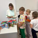 bibliotekarka pomaga dzieciom robić wachlarze