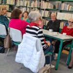 seniorzy siedzą przy długim stole