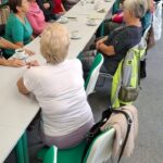 seniorzy siedzą przy długim stole